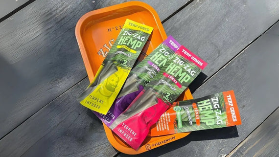 Chemical-free rolling cones Zig-Zag terpene-infused hemp packs displayed on an orange tray over a dark wooden surface.