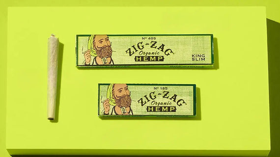 Hemp cones for smoking shown with Zig-Zag organic hemp papers in King Slim and standard sizes on a bold green background.