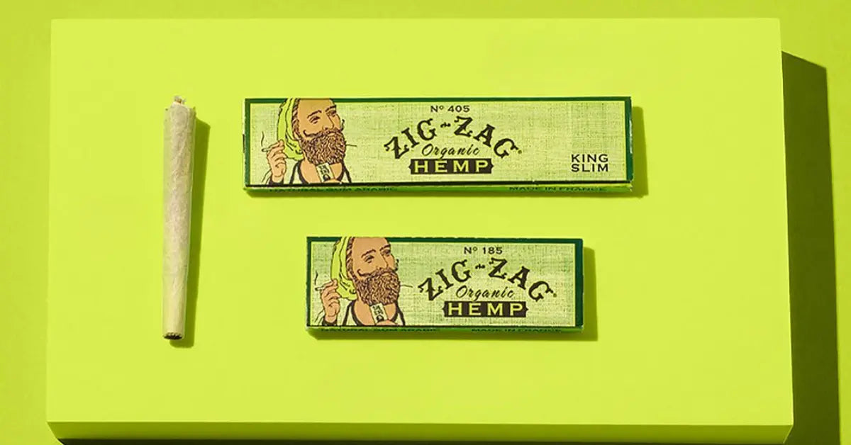 Hemp cones for smoking shown with Zig-Zag organic hemp papers in King Slim and standard sizes on a bold green background.