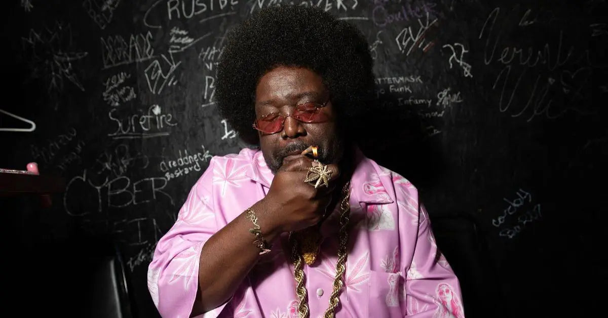 Slow-burning rolling paper being lit by a man in a pink patterned shirt against a chalkboard wall