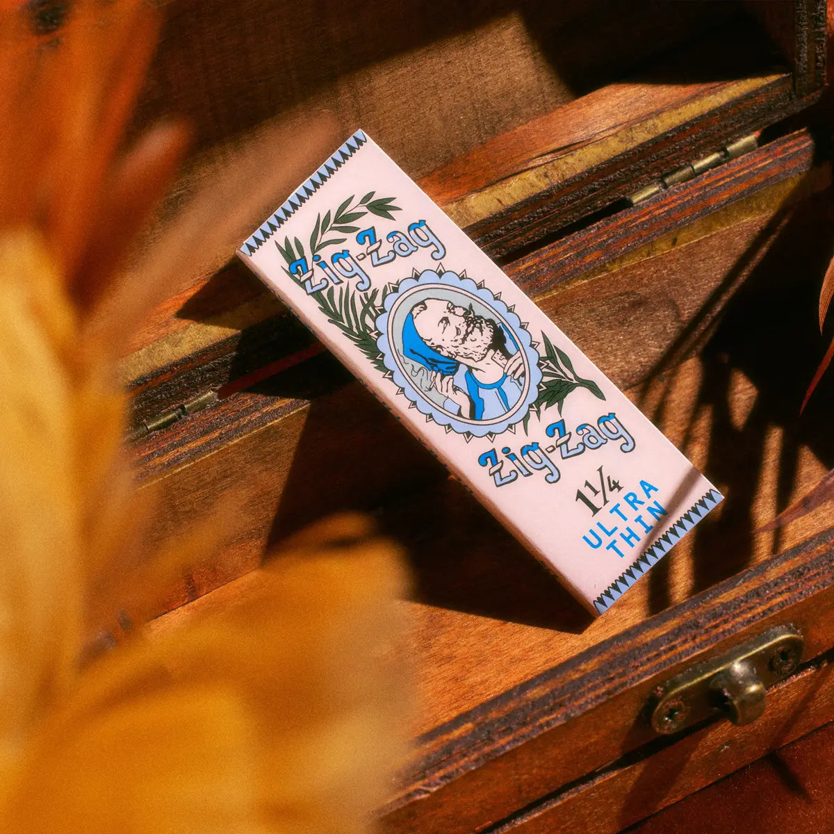 Zig-Zag 1 1/4 Ultra Thin rolling papers displayed on a wooden surface with a warm, natural backdrop.