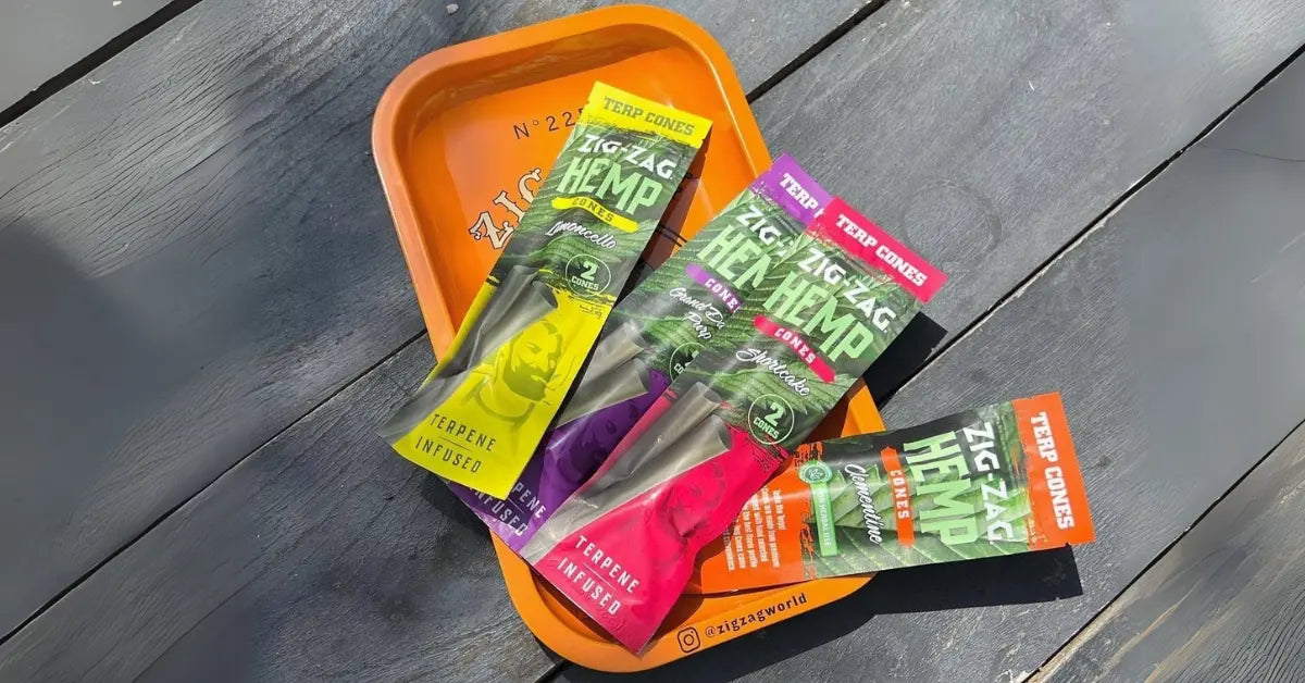 Chemical-free rolling cones Zig-Zag terpene-infused hemp packs displayed on an orange tray over a dark wooden surface.