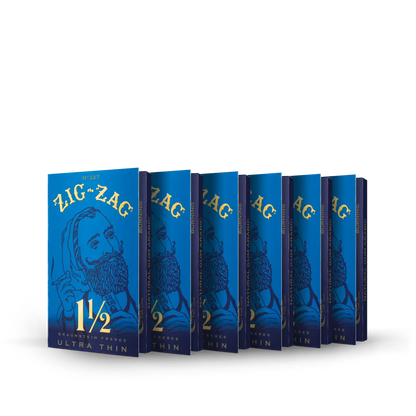 Ultra thin rolling papers in Zig-Zag 1½ size blue packs, arranged in a row with gold lettering on a dark background.