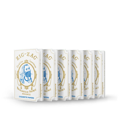 Cigarette papers in Zig-Zag Qualité Supérieure white and gold packs, displayed in a row on a dark green background.