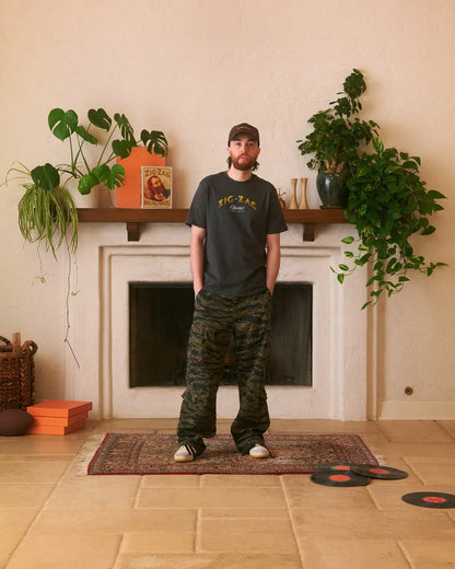 Front view of a Zig-Zag t-shirt with "Zig-Zag Classic" text, styled simply with camo pants and a cap.