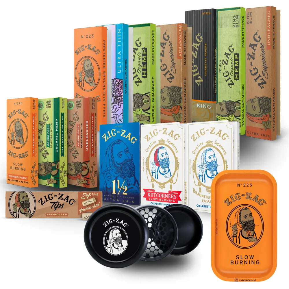 Hemp cones and rolling papers in assorted Zig-Zag packaging with branded grinder and orange rolling tray on white background.
